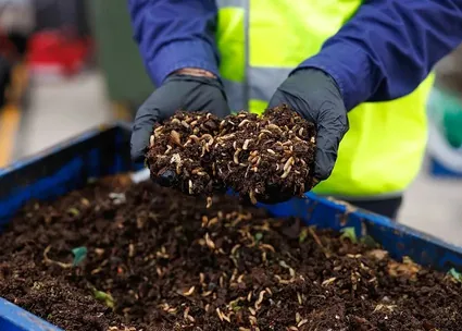 Gloved hands holding processed compost